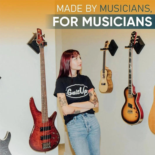 Woman standing by wall-mounted guitars, bass, and ukulele using easy hangers, modern music room.