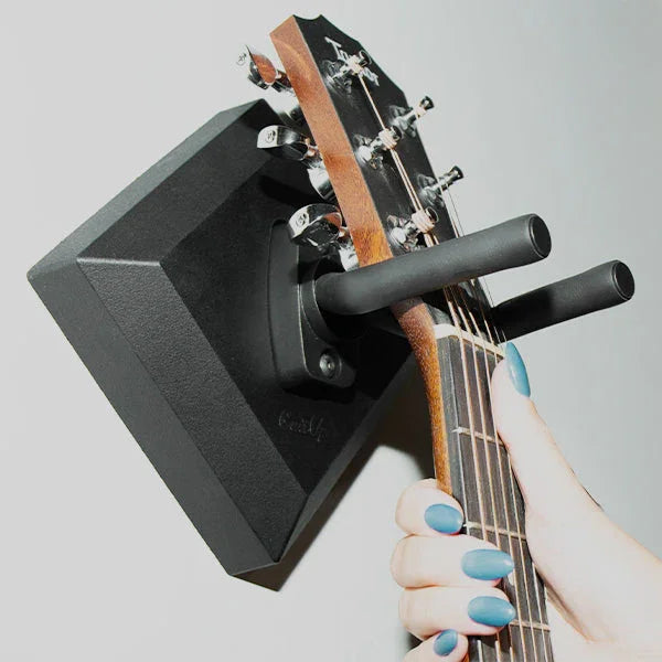 Hand placing acoustic guitar on easy wall hanger mount