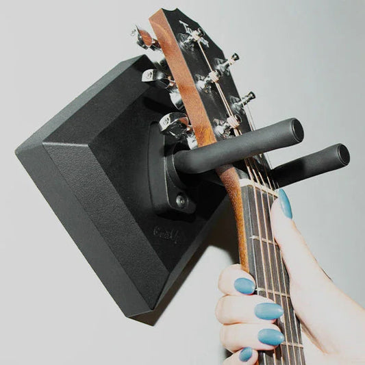 Hand placing acoustic guitar on easy wall hanger mount